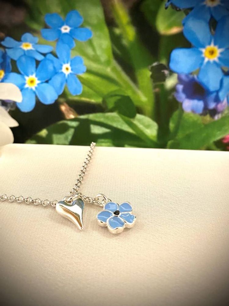 Kort smykke sølvfarget med hjerte og blå blomst